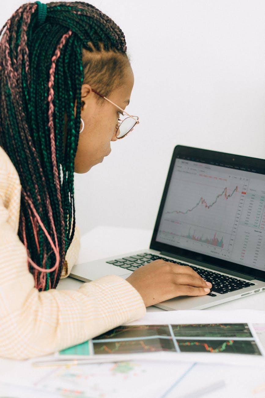 woman in a beige jacket analyzing the graph on her laptop